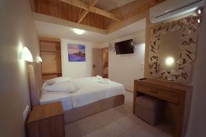 a bedroom with a white bed and a wooden ceiling at Rouda Bay Beach Hotel in Mikros Gialos