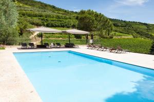 a swimming pool with chairs and an umbrella at Massimago Wine Relais in Mezzane di Sotto