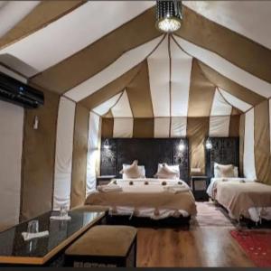 een grote kamer met 2 bedden en een kroonluchter bij Layalée Luxurycamp in Merzouga
