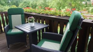 two chairs and a table on a deck with flowers at Urlaub mit Alpakas in Sabrodt
