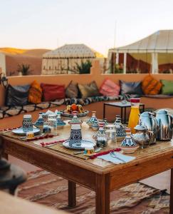 een houten tafel met borden en borden erop bij Layalée Luxurycamp in Merzouga