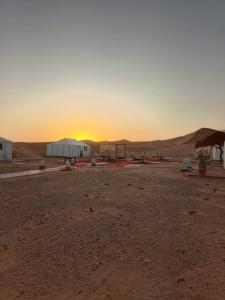 een zonsondergang in de woestijn met tenten in een veld bij Layalée Luxurycamp in Merzouga