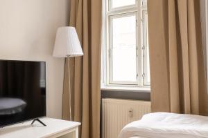 a room with a bed and a television and a window at Authentic Copenhagen Apartment for 4 Guests in Copenhagen +35 photos
