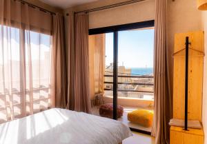 a bedroom with a bed and a view of the ocean at SURFHALLA Morocco in Imsouane