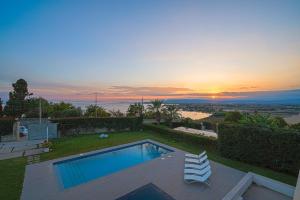 una piscina con 2 sillas y una puesta de sol en Villa Opulentia piscine vista mare, en Plemmirio