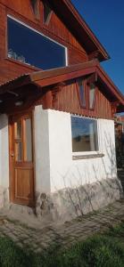 a house with a wooden door and a window at Casa del Sol in Trevelin