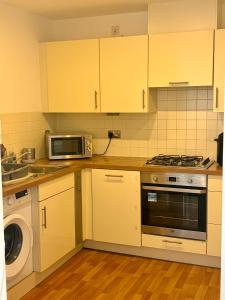 Una cocina con gabinetes amarillos, un microondas y una lavadora. en 1 Bedroom Flat near Excel, O2, Canary Wharf - London, en Londres