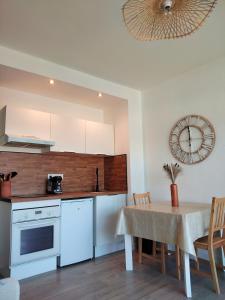 a kitchen and dining room with a table and a clock at Le Galop Bleu in Cagnes-sur-Mer
