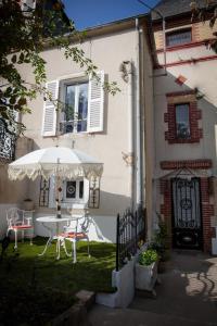 a table with an umbrella in front of a house at Au Petit Chateau les Bains in Morvan in Saint-Honoré-les-Bains