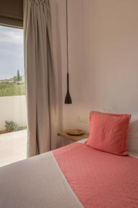 a bed with a pink pillow next to a window at Peratzada in Tsilivi +98 photos