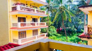 a yellow building with balconies and palm trees at 3bhk Villa calangute in Calangute