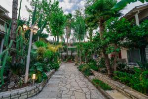 a walkway through a garden with trees and plants at Rouda Bay Beach Hotel in Mikros Gialos