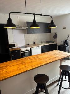 a kitchen with a wooden counter top and two stools at Appartement centre ville in Langres