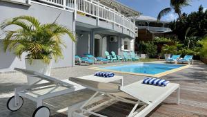 Villa con piscina con sillas y mesa. en Ti Paradi, villa 12 pers, 2 piscines, vue golf mer, en Les Trois-Îlets
