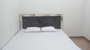 a bedroom with a white bed with two pillows at Radha Rani Dham in Rādha Kund