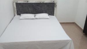 a white bed with two pillows on top of it at Radha Rani Dham in Rādha Kund