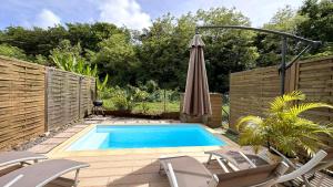Quartiers Anse à lʼÂneにあるLAKAYOU, 4 pers, piscine privee, plageの裏庭にパラソルと椅子のあるプール