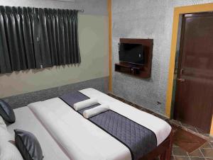 a bedroom with a bed and a tv in it at Misty Valley Inn in Kodaikānāl