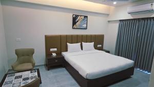 a hotel room with a bed and a chair at Hotel The Golden Oaks, Kolhapur in Kolhapur +35 photos