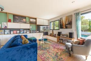 a living room with a blue couch and two chairs at Villa Sunrise – Villa contemporaine avec piscine et vue panoramique sur le lac d’Annecy in Veyrier-du-Lac