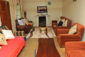 a living room with several couches and a fireplace at Nancy's Farm House in Chuka