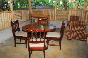 a wooden table and four chairs and a table and chair at Nancy's Farm House in Chuka