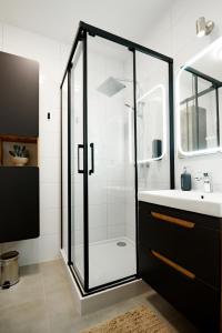 a bathroom with a glass shower and a sink at Apartamenty EUROPA in Jasło
