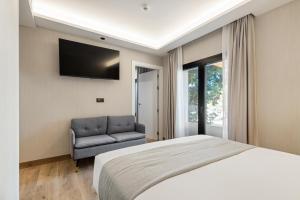 a bedroom with a bed and a chair and a television at Dobo Madrid Ricardos in Madrid