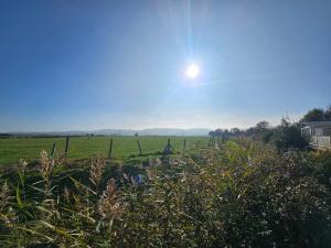 ein Grasfeld mit der Sonne am Himmel in der Unterkunft Park Dean Resorts Premium plot with Mountain view & Decking in Abergele