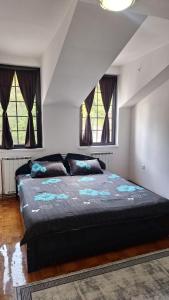 a bedroom with a large bed and two windows at Atika in Cazin