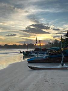 un grupo de barcos sentados en la playa al atardecer en One More Day Hostel, en Weligama