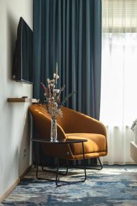 a living room with a couch and a vase with flowers on a table at Hotel Bronzo Brno in Brno