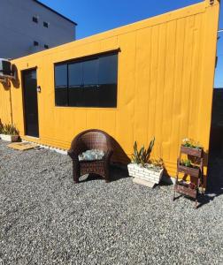 a yellow building with a wicker chair in front of it at Conteiner Beira Mar Solar Analuz Prox Beto Carrero in Navegantes