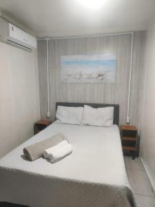 a bedroom with a white bed with two towels on it at Conteiner Beira Mar Solar Analuz Prox Beto Carrero in Navegantes