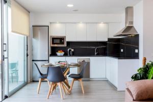 a kitchen with white cabinets and a table and chairs at Home2Book Coastal Calm Las Eras Patio Rooftop in Las Eras