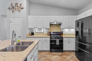 a kitchen with white cabinets and a sink and a stove at The Deserts Best Kept Secret by Navigate Stays in Desert Groves Mobile Home Park +22 photos