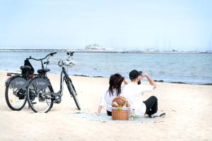 a couple sitting on the beach next to a bike at Rezydent Hotel Sopot - MGallery Collection in Sopot