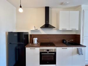 a kitchen with a black refrigerator and white cabinets at Appartement duplex centre-ville entièrement rénové in Mortagne-au-Perche +4 photos