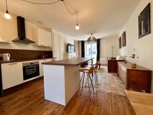 a kitchen with white cabinets and a wooden floor at Appartement duplex centre-ville entièrement rénové in Mortagne-au-Perche