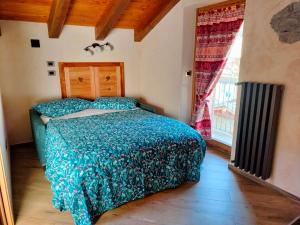 a bedroom with a bed with a green comforter and a window at La Lune de Saint George in Hone