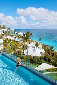 a woman sitting on the edge of a swimming pool at a resort at Azura Bermuda in Bermuda