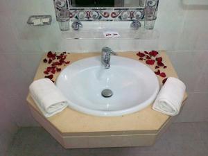 a bathroom sink with red flowers on a counter at Real Caparica Hotel in Costa da Caparica