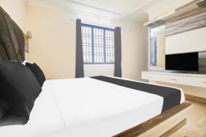 a bedroom with a white bed and a flat screen tv at Hotel O Subash Inn in Jalandhar