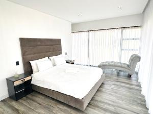 a white bedroom with a large bed and a chair at Sucassa 54 - Luxury 2 Bedroom - Dam & Mountain View in Hartbeespoort +3 photos