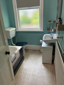 a bathroom with a sink and a toilet and a window at Grace Stays in Ellesmere Port