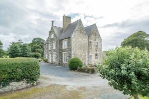 an old stone building with a chimney and bushes at Ficerdy in Llanwnda