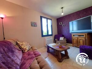 a living room with a couch and a flat screen tv at L'Escapade in Gagnac