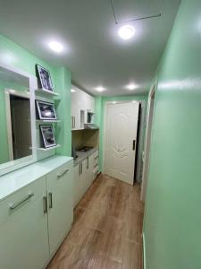 una cocina con armarios blancos y paredes verdes en فلورينزا الخمسين, en Hurghada