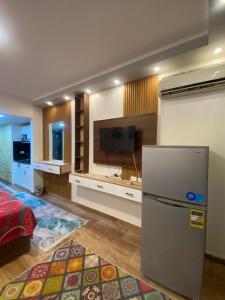cocina con nevera y TV de pantalla plana. en فلورينزا الخمسين, en Hurghada