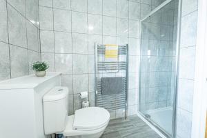 Un baño blanco con inodoro y ducha. en Stunning 4-Bed Beachfront Home Sea Views in Dymchurch, en Dymchurch 10 fotos más
